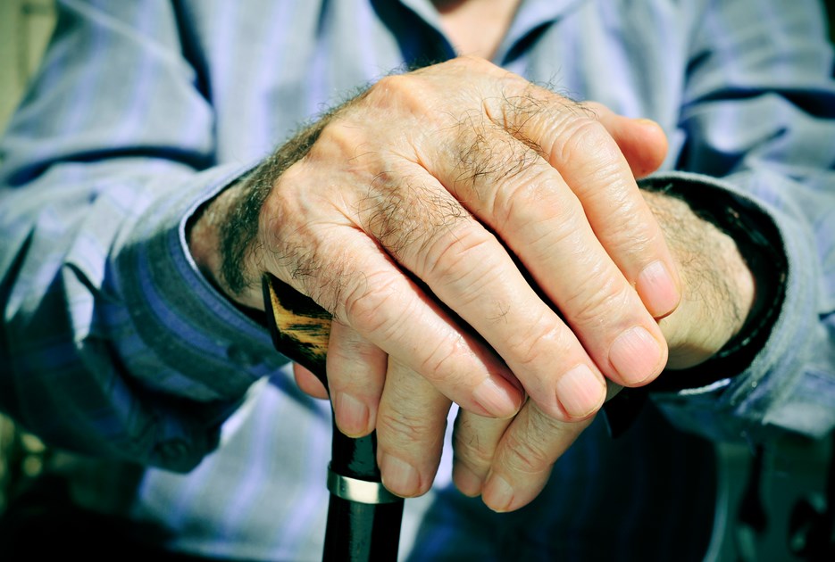 Ældre person med hænder på en stok